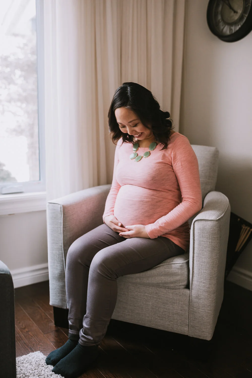 pregnant woman sits in chair touching baby bump - stouffville lifestyle photography