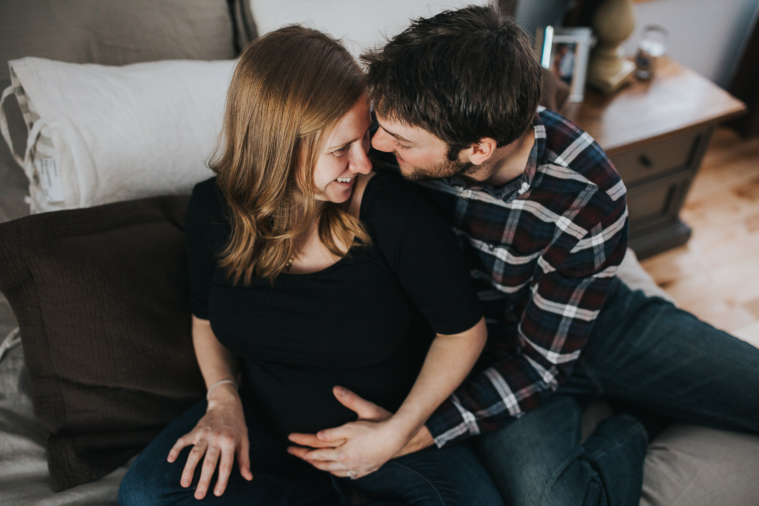 pregnant woman and husband snuggle on bed - Newmarket lifestyle photography