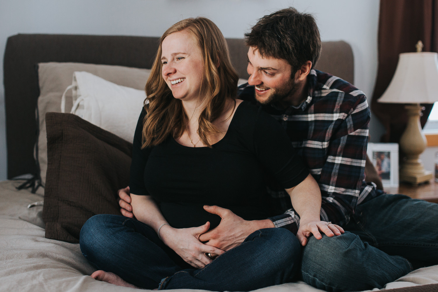 pregnant wife and husband laughing on bed - Markham lifestyle photography