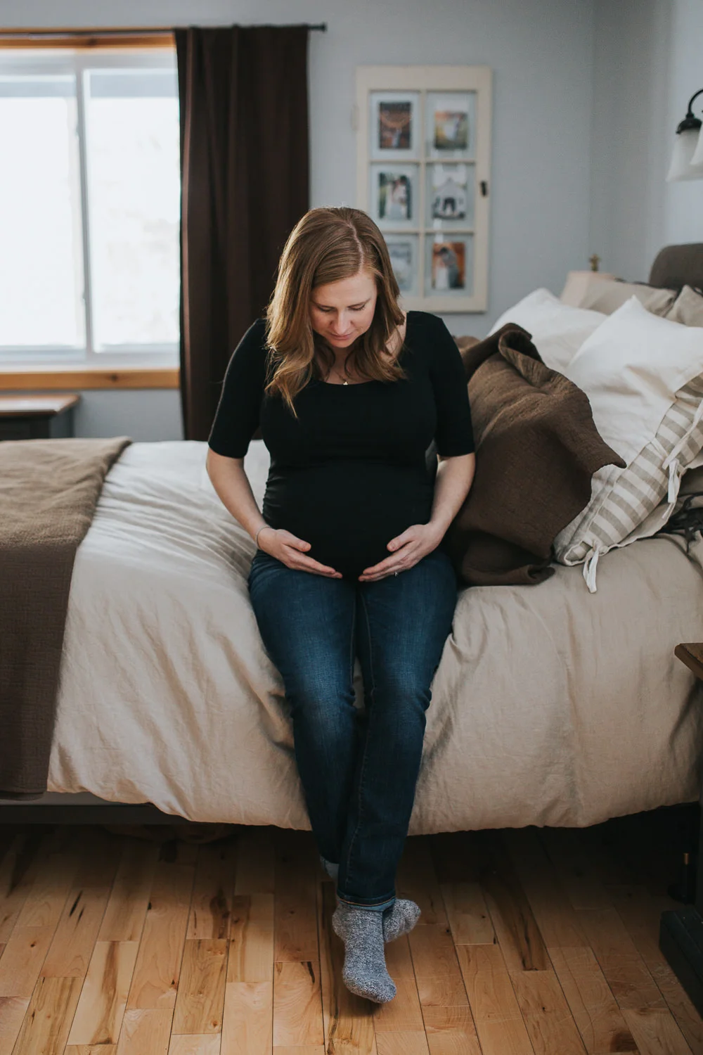 pregnant mom to be sitting on side of bed looking at baby bump - uxbridge lifestyle photos
