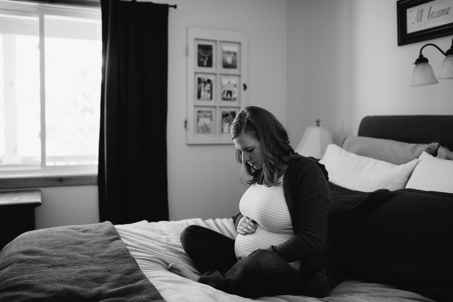 pregnant mom to be sitting on bed holding baby bump - Newmarket in-home photography