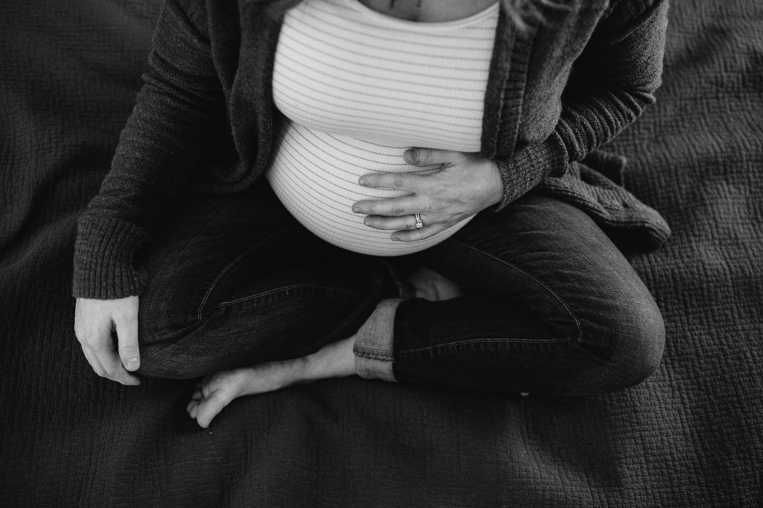 pregnant mom to be sitting on bed holding baby bump - Markham in-home photography