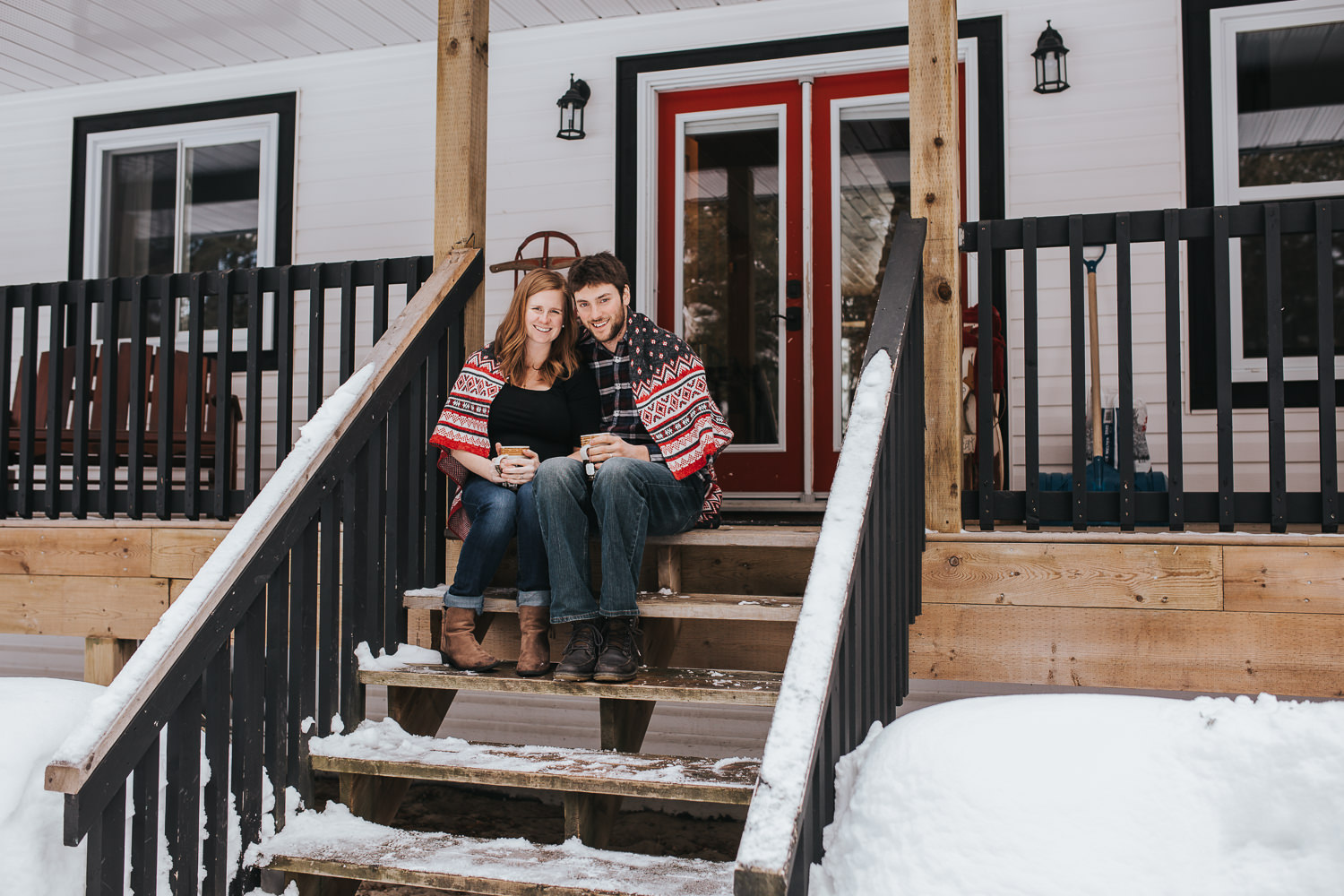 parents to be sitting on front porch steps wrapped in blanket looking at camera  - Markham lifestyle photos