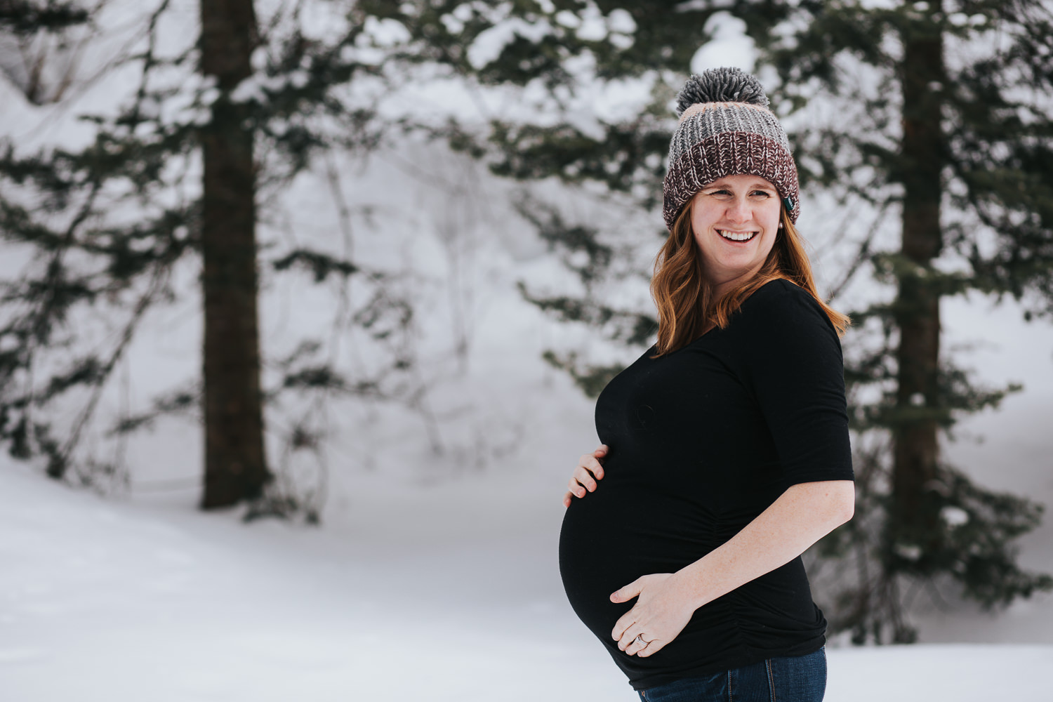 blonde pregnant woman holds baby bump and smiles into distance - Stouffville lifestyle photos