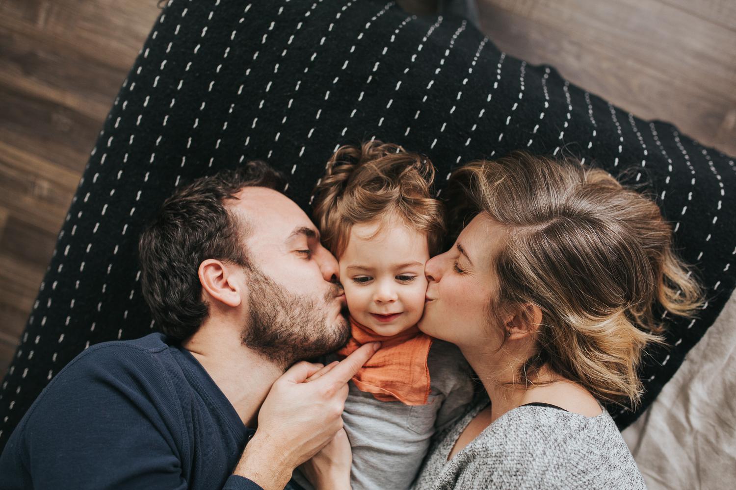 family of 3 with 2 year old toddler boy laughing and lying on bed - stouffville in-home family photos