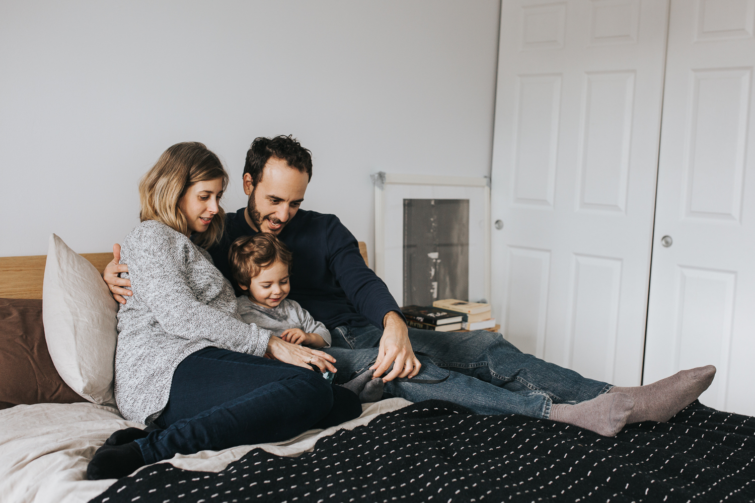 family of 3 with 2 year old toddler boy and pregnant mother snuggle on bed - stouffville in-home family photography