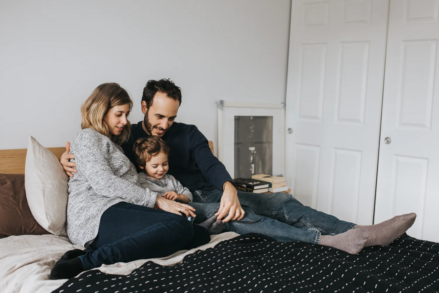 family of 3 with 2 year old toddler boy and pregnant mother snuggle on bed - stouffville in-home family photography