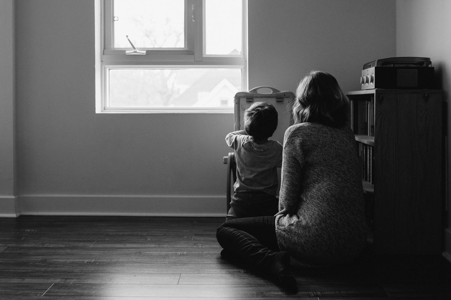 pregnant mom with short blonde hair helps 2 year old toddler son draw on easel - newmarket in-home family photography 