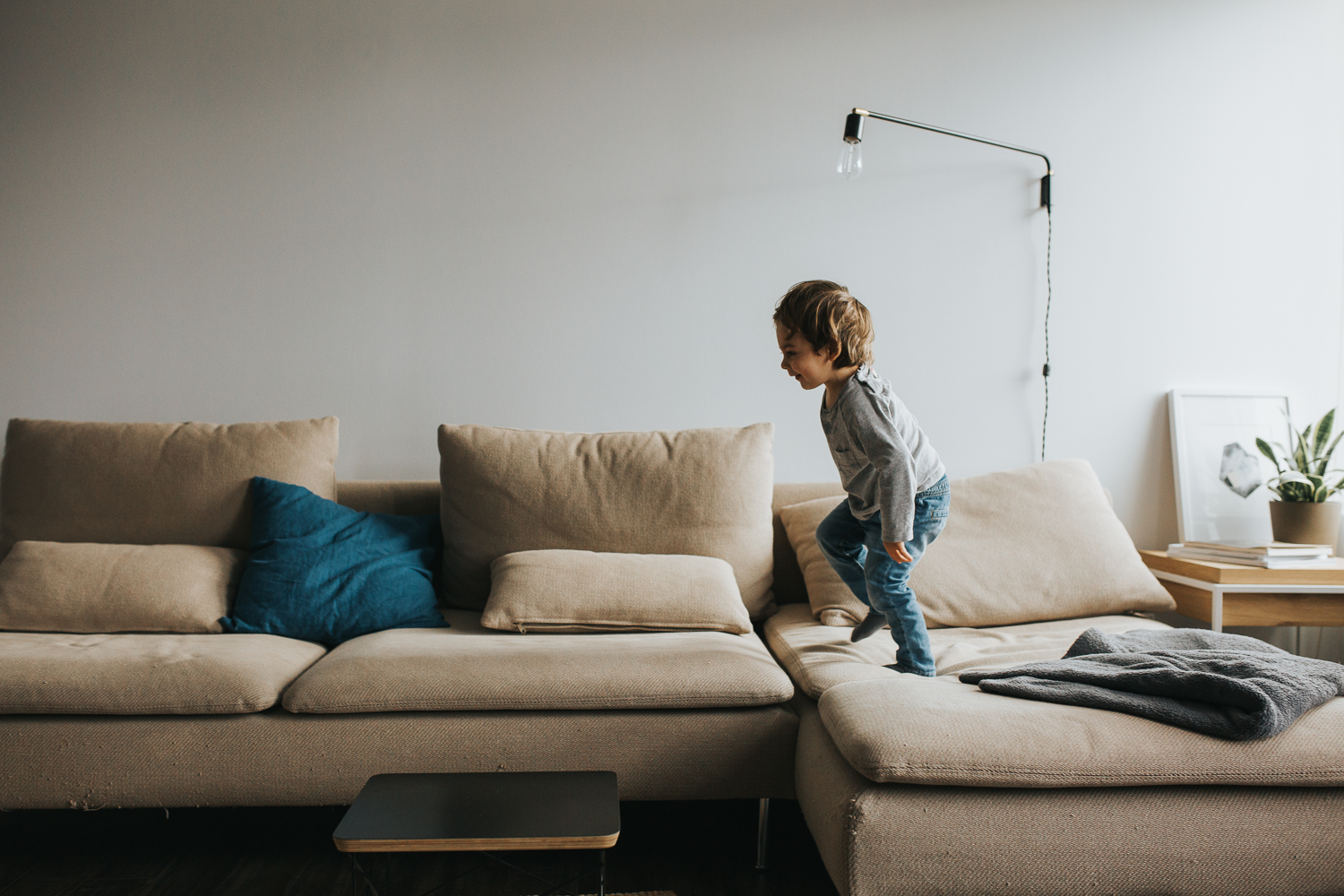 2 year old brunette toddler boy runs across sectional couch - markham in-home family photos