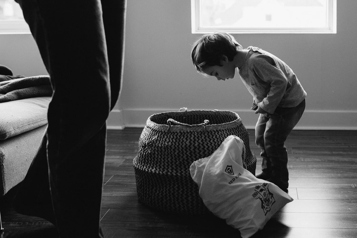 2 year old brunette toddler boy looks into basket for toys - uxbridge in-home family photos