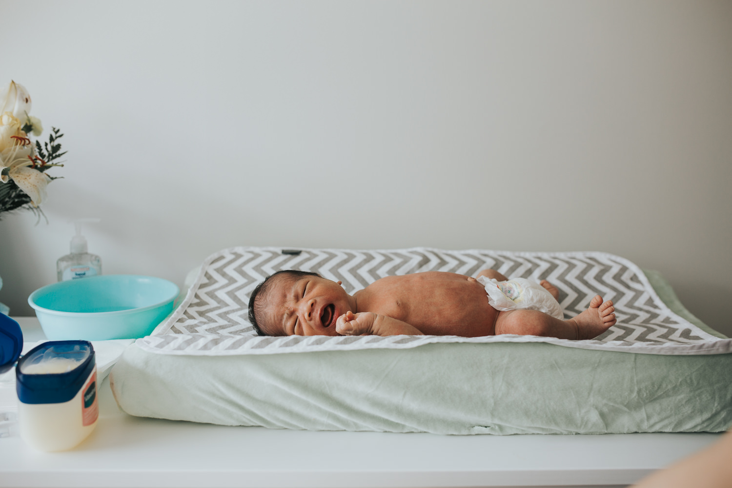 2 week old baby boy lying on green changing pad in diaper - Markham in-home photos