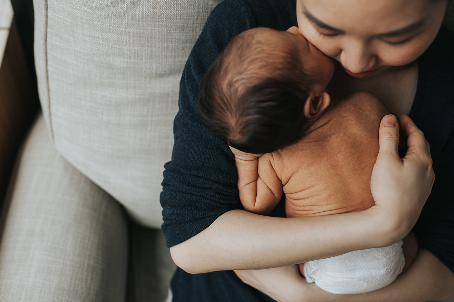 2 week old baby boy in diaper being hugged by mother in rocking chair - Markham in-home photography