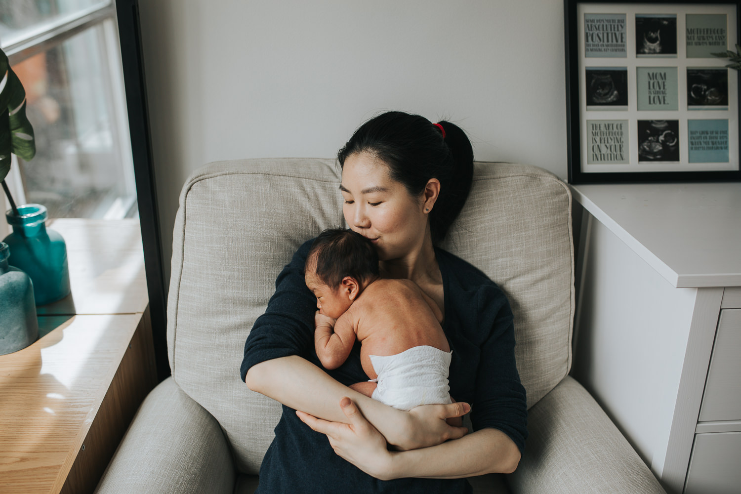 mom holding and kissing 2 week old baby boy in rocking chair - Stouffville lifestyle photos