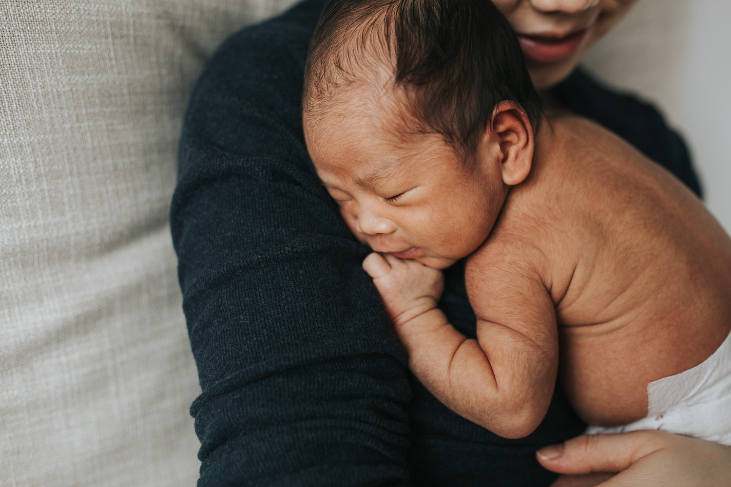 2 week old baby boy in diaper held by mother in rocking chair - Stouffville in-home photography