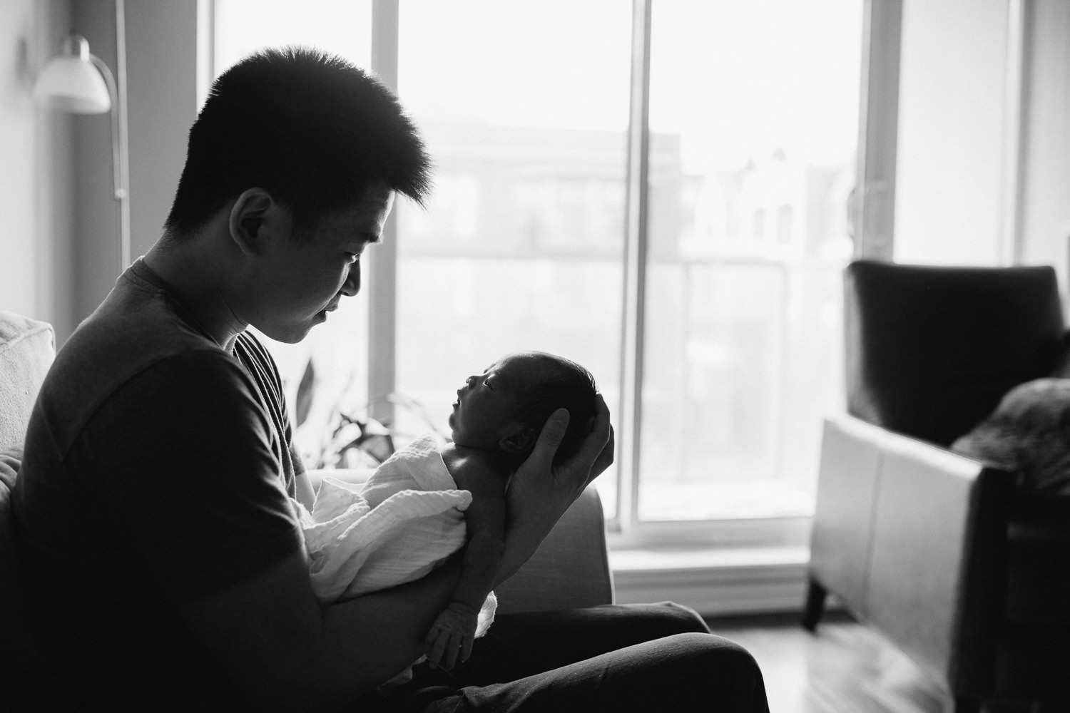 first time dad holding and looking at 2 week old baby son - Markham in-home photography