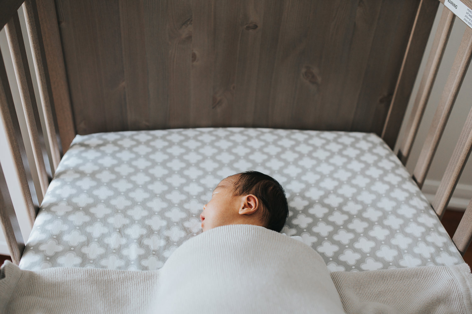 2 week old baby boy with dark hair sleeping in nursery crib - Barrie lifestyle photos