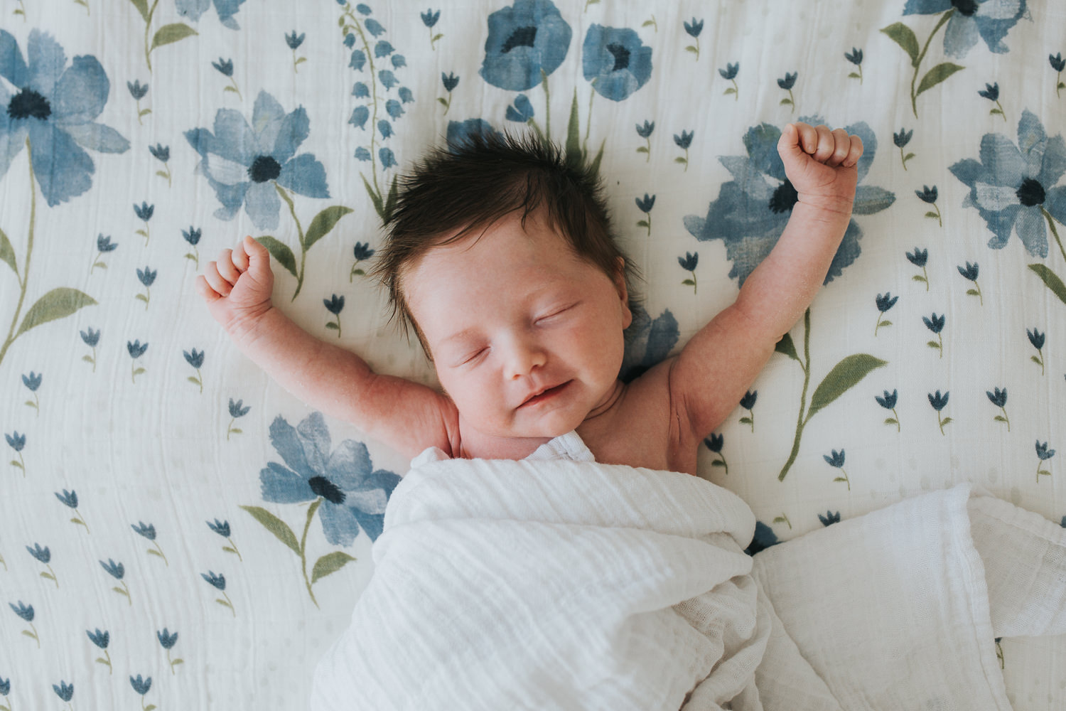 2 week old baby girl with lots of dark hair lying on bed and stretching arms - Stouffville lifestyle photography