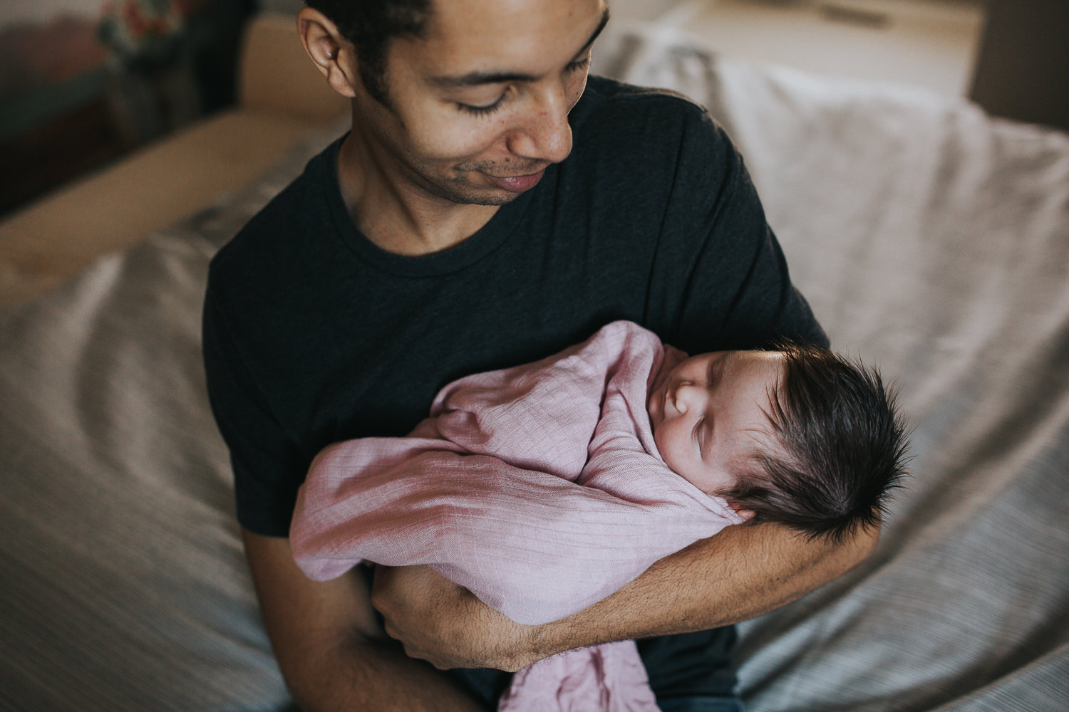 new dad holding and looking at 2 week old baby girl - Markham in-home photography session