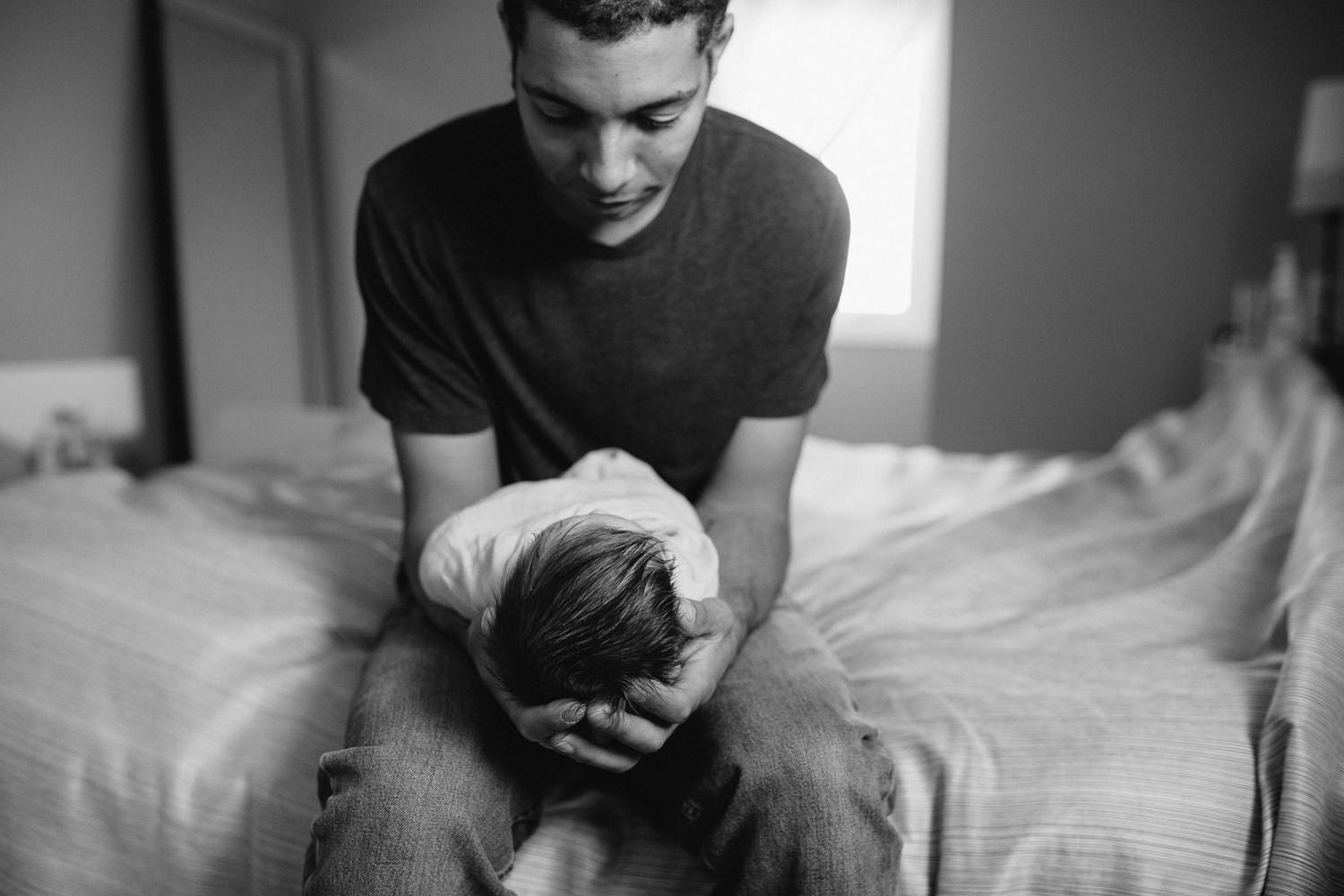 new dad holding and looking at 2 week old baby girl - Markham lifestyle photography session