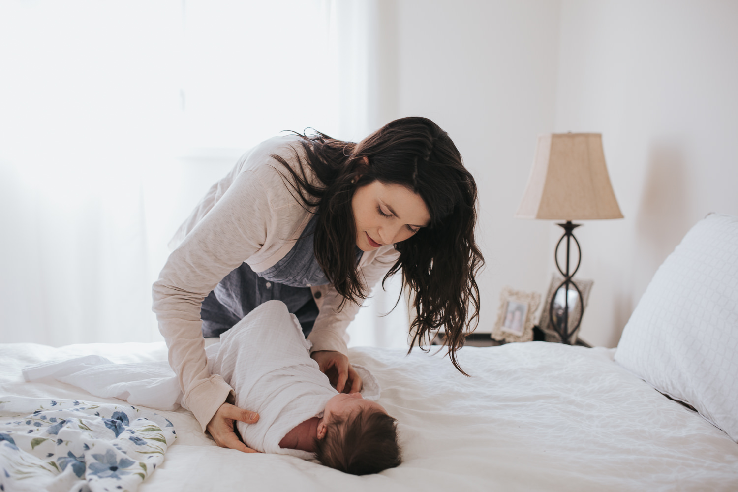 mother swaddling 2 week old baby girl on bed - Barrie lifestyle photos