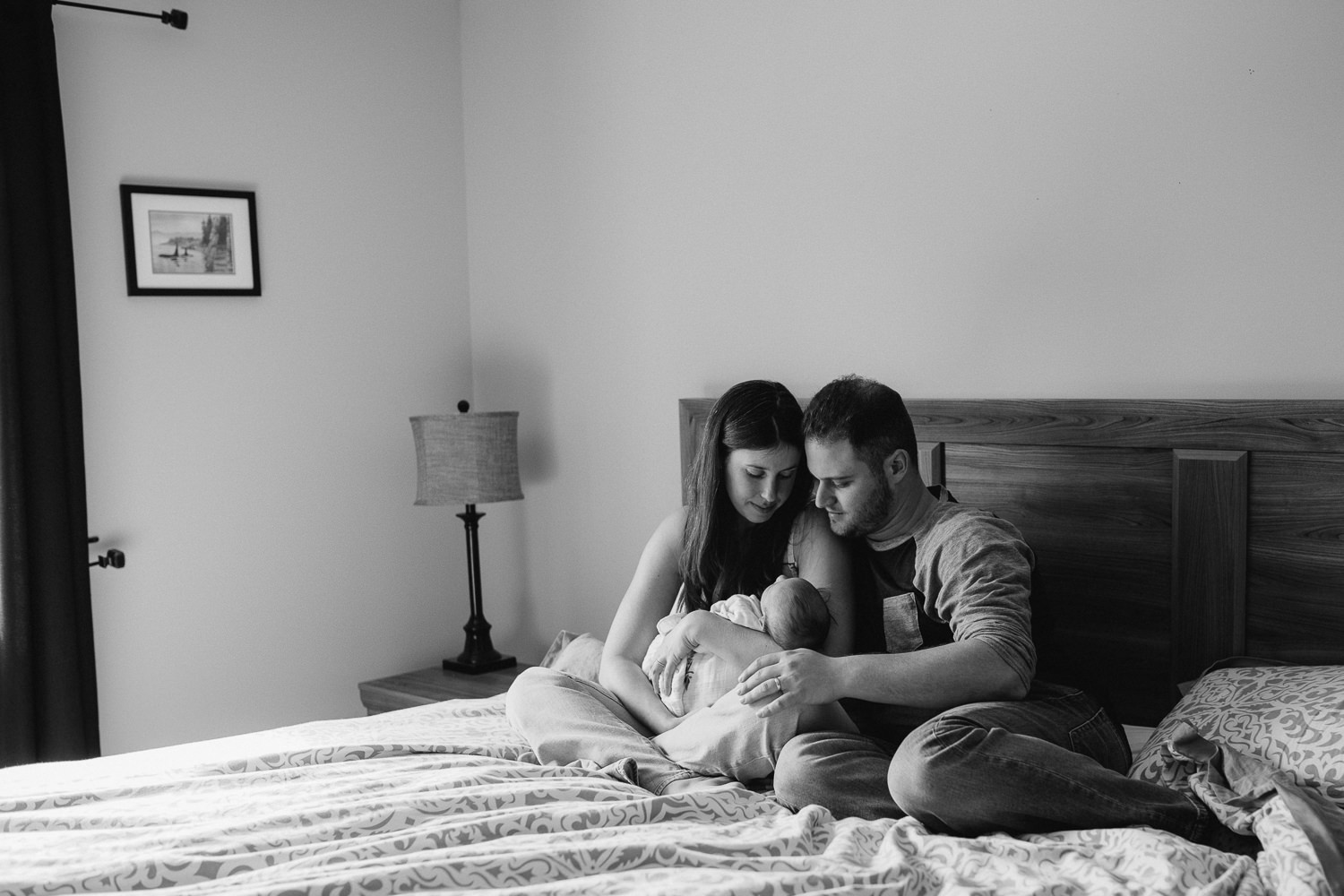 mom and dad snuggling 6 week old baby girl in bed - Stouffville in-home photography