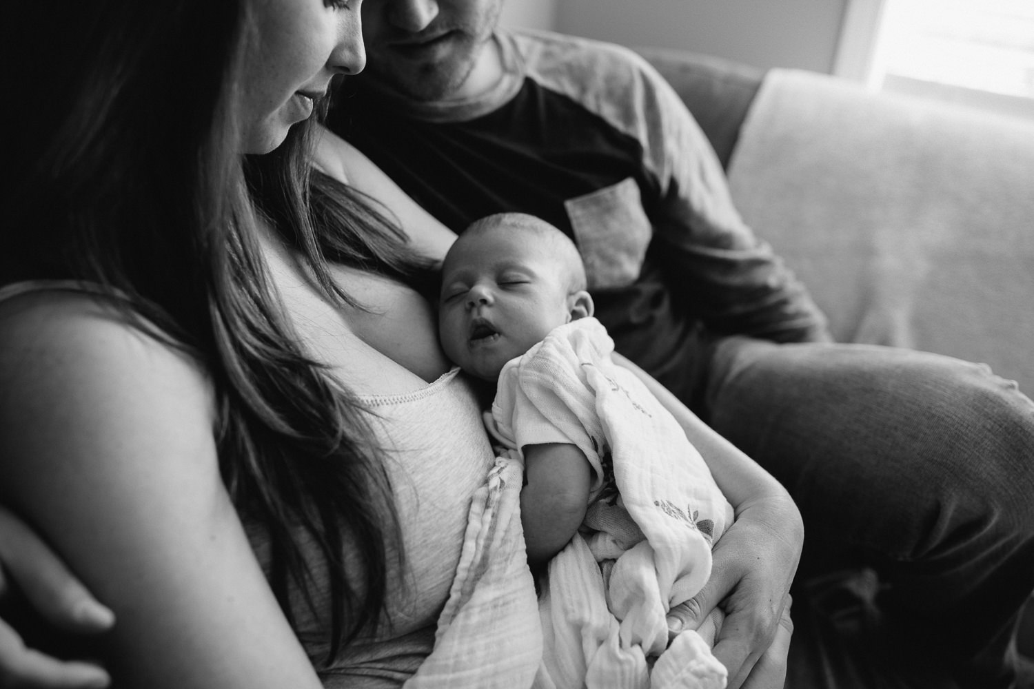 new parents sitting on couch holding and looking at 6 week old baby girl - Newmarket lifestyle photography