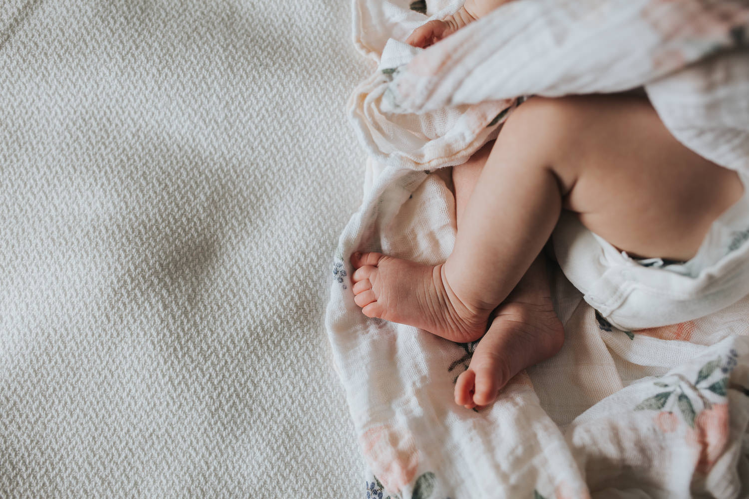 6 week old baby girl feet in flower swaddle lying on bed - Barrie lifestyle photography