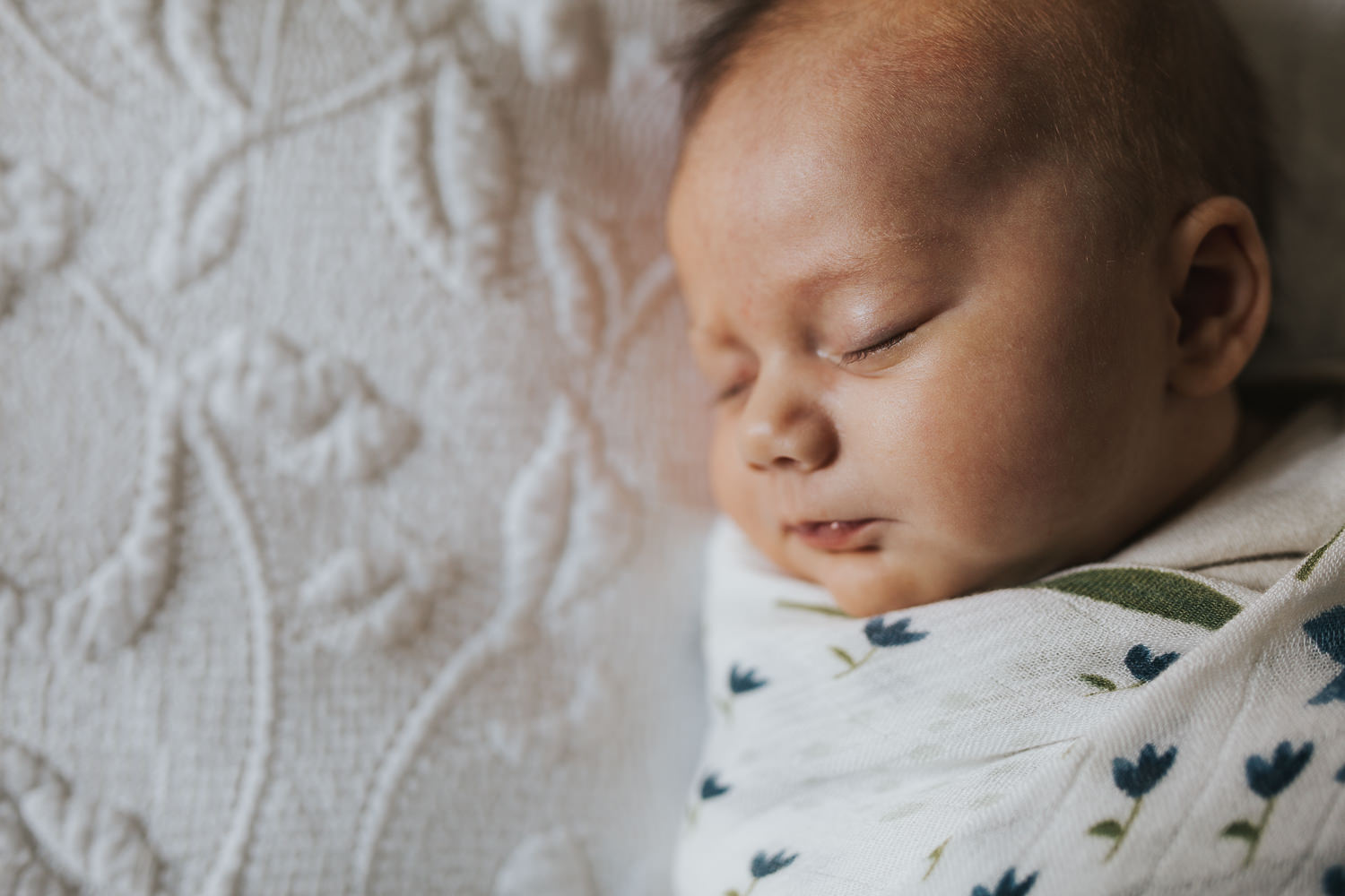 5 week old baby girl swaddled in blue flower blanket asleep on bed - Newmarket in-home photos