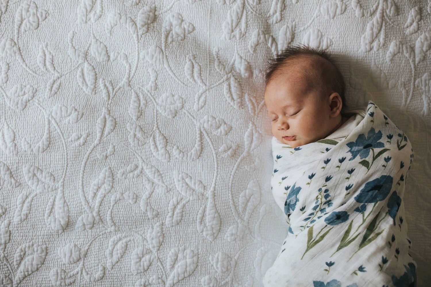 5 week old baby girl swaddled in blue flower blanket asleep on bed - Barrie lifestyle photos