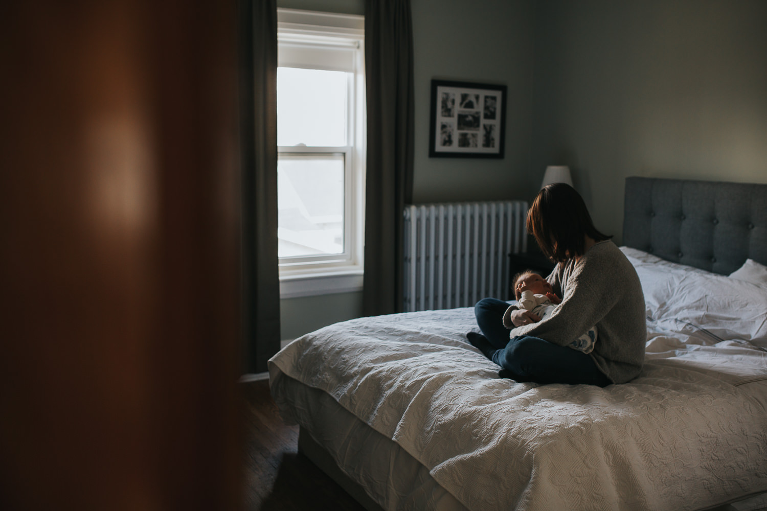 mom holding 5 week old baby girl in master bedroom, sitting on bed - Stouffville in-home photos