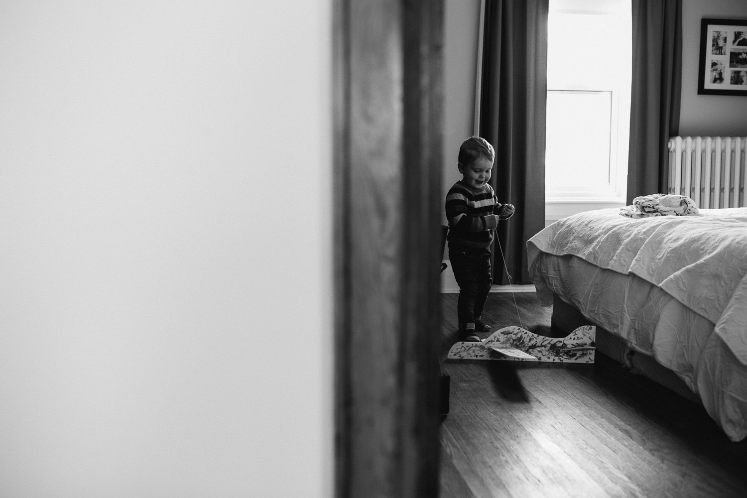 3 year old toddler boy pulling toy plane around in parent's bedroom - Stouffville lifestyle photography