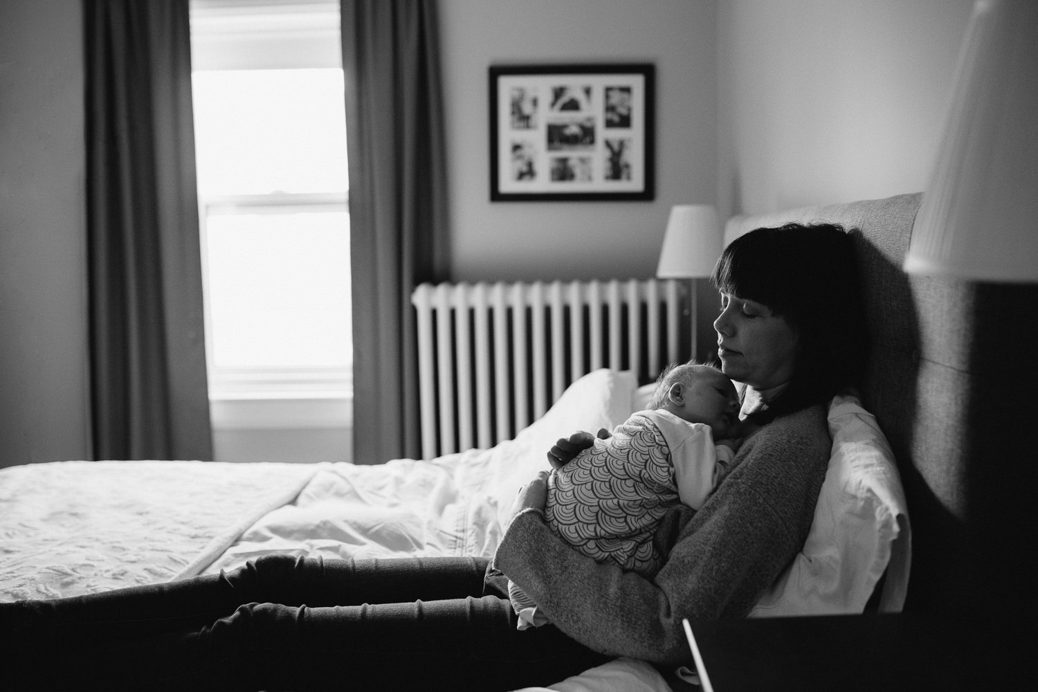 mom sits on master bed holding 5 week old baby daughter to her chest, eyes closed - Barrie lifestyle photography