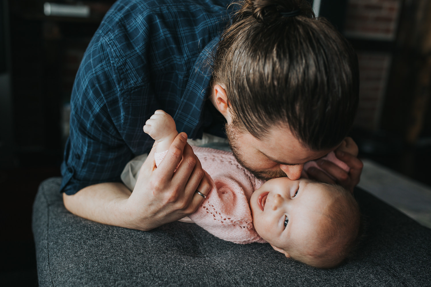 5 month old baby girl laughing, lying on couch as dad kisses her - Stouffville lifestyle photography