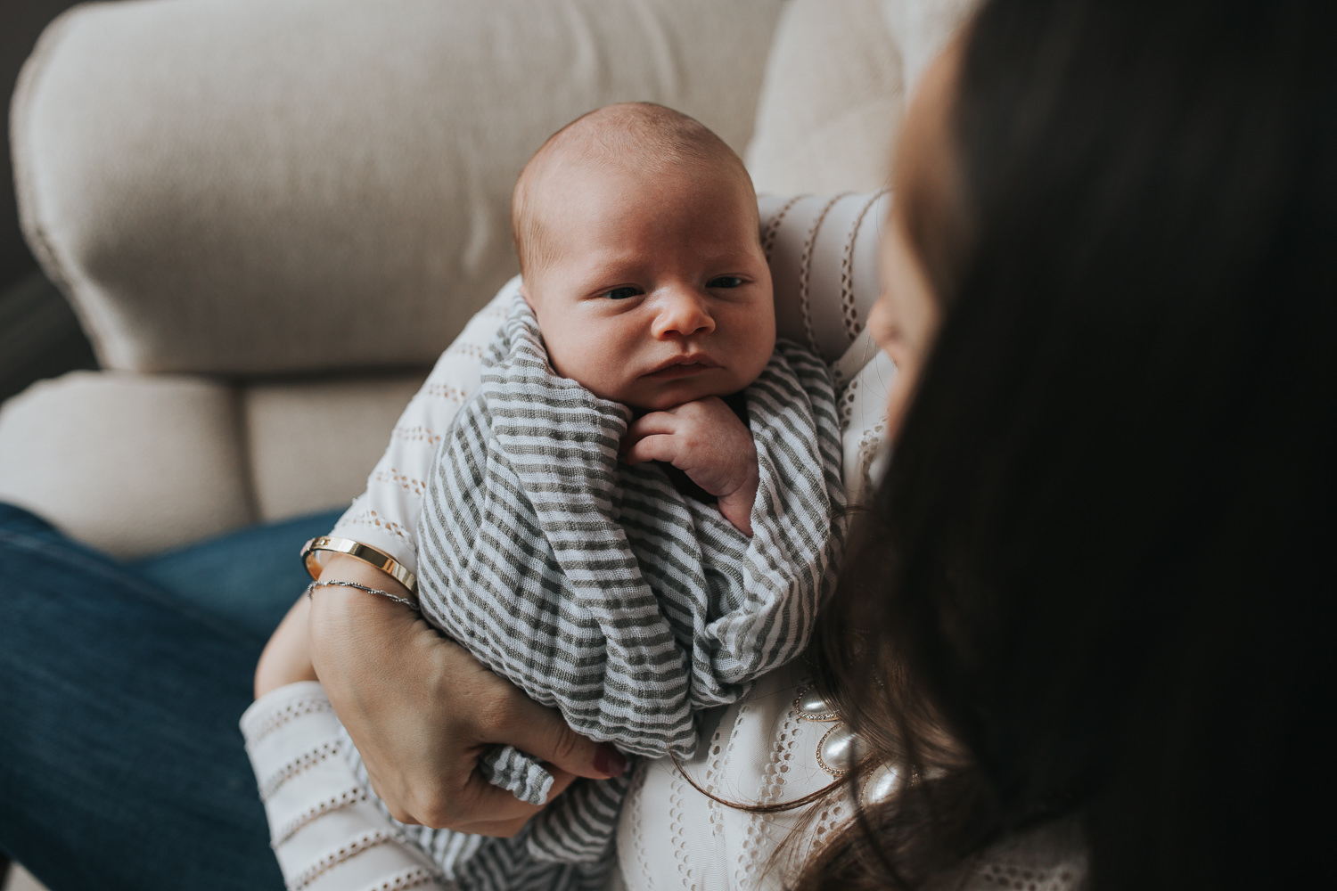 2 week old baby boy lying in mom's arms, looking up at mother - Markham in-home photos