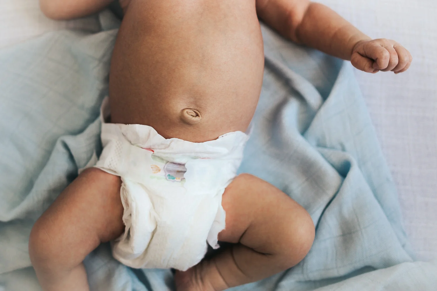 2 week old baby boy's bellybutton lying on blue swaddle - Stouffville in-home photography