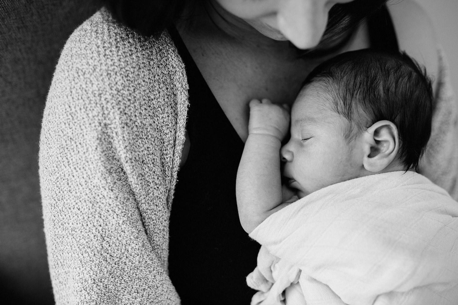 brunette mother holding sleeping 2 week old baby boy on chest in rocking chair - Uxbridge In-Home Photography