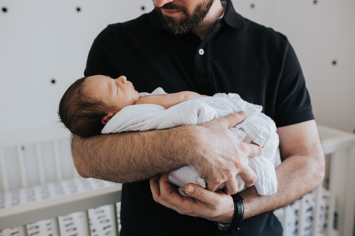 new dad holding and looking at sleeping 2 week old baby boy in nursery - Stouffville lifestyle photos 