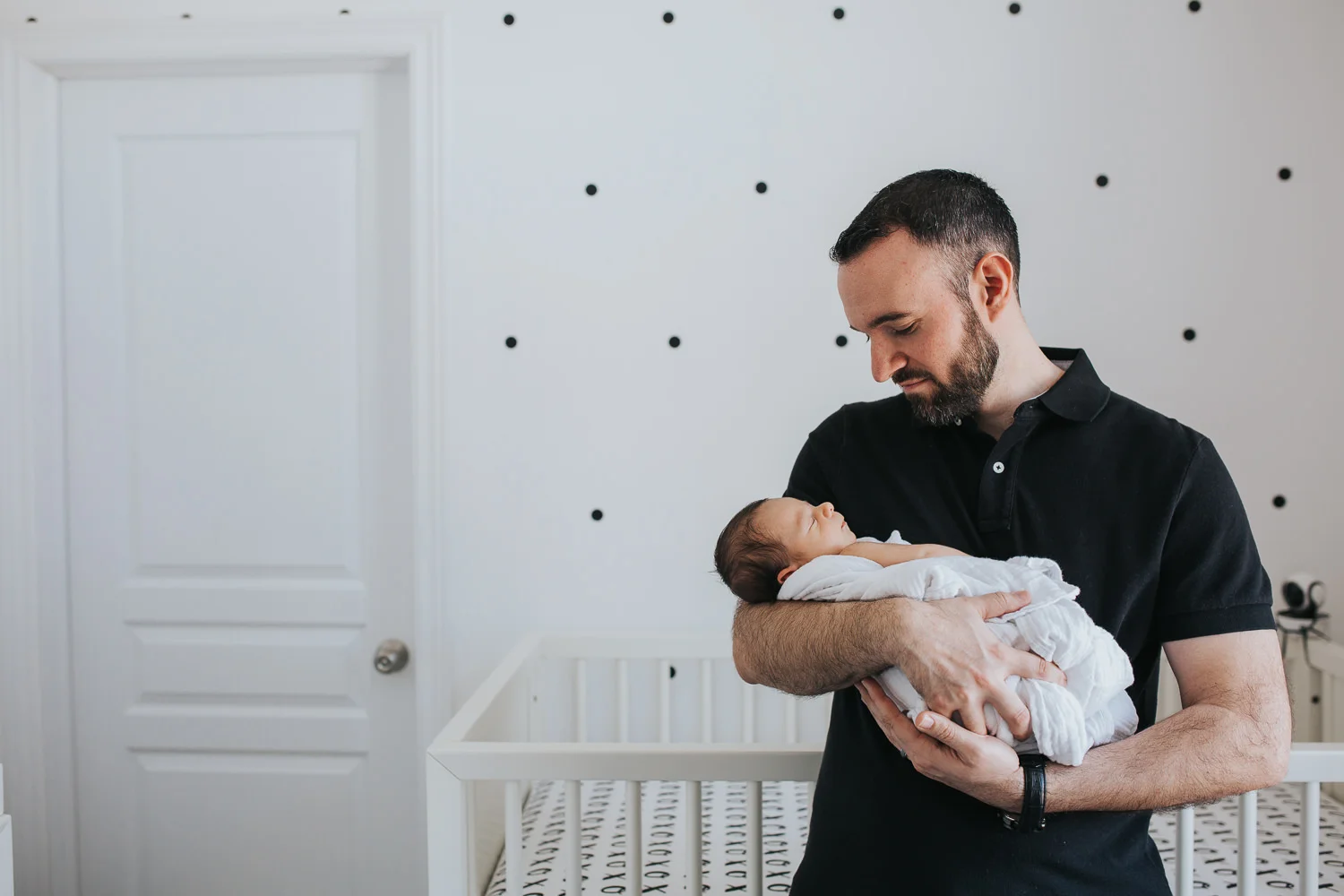 new dad holding and looking at sleeping 2 week old baby boy in nursery - Markham lifestyle photos