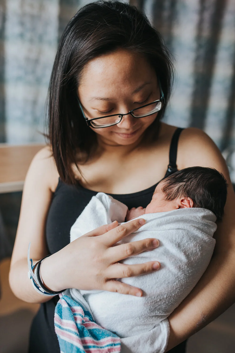 new mother holding sleeping 1 day old baby son to chest, swaddled in hospital blanket - Markham Fresh 48 Photography