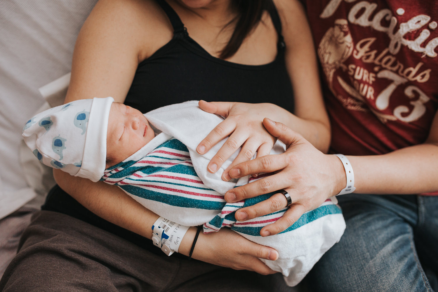 new parents sitting in hospital bed holding newborn baby boy - Uxbridge Fresh 48 Photography