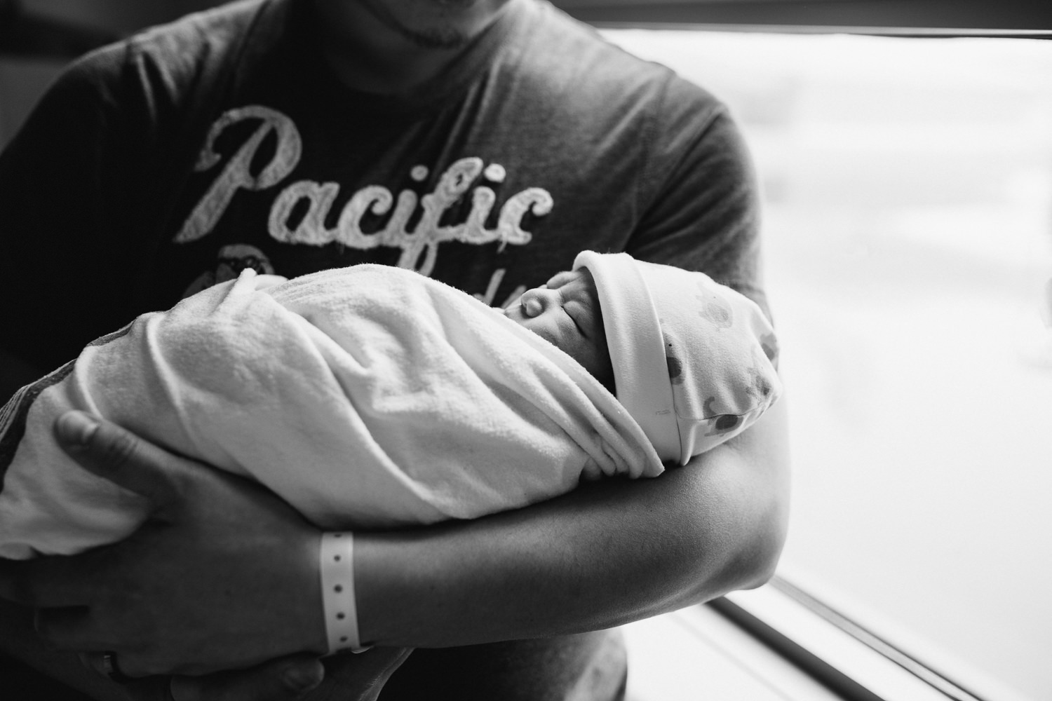 new dad standing and holding 1 day old baby boy in hospital swaddle - Newmarket Fresh 48 Photos