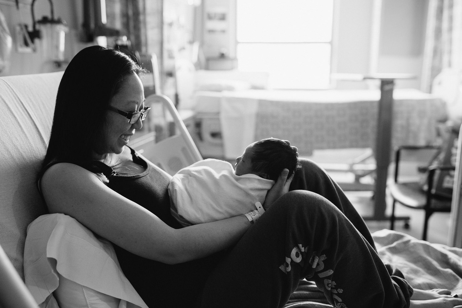 new mom sitting on hospital bed holding and admiring 1 day old baby son - Newmarket Fresh 48 Photography 