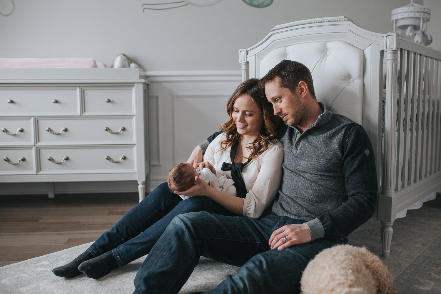 first time parents sitting on nursery floor holding 2 week old baby daughter - Markham Lifestyle Photos