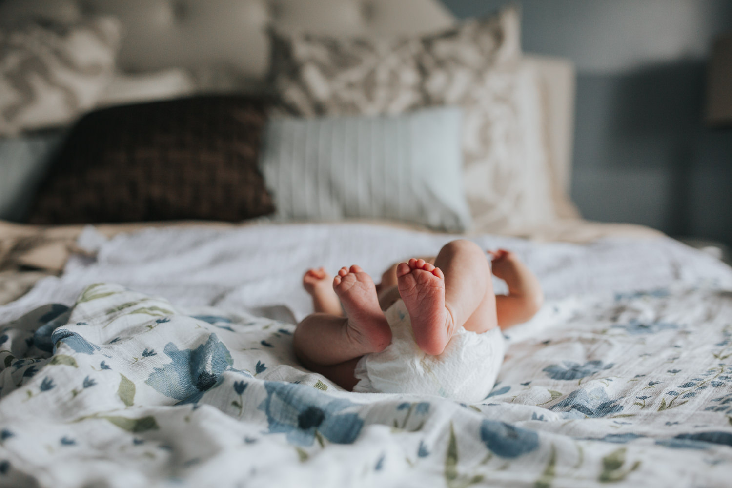 2 week old baby girl lying on bed in diaper with feet in air - Barrie In-Home