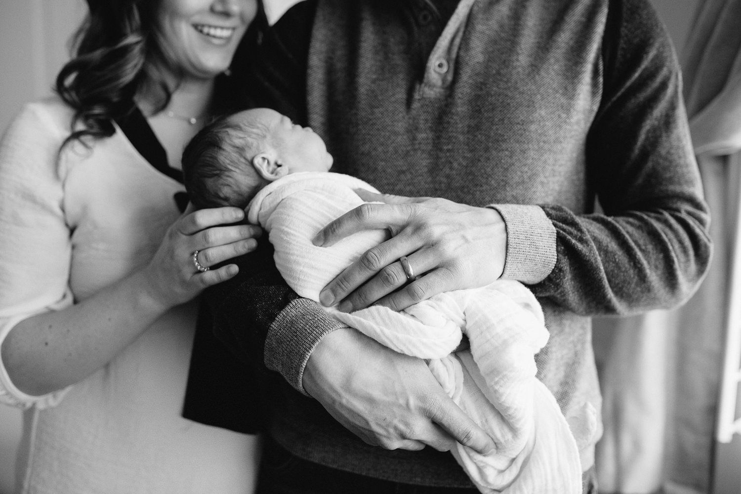 new parents standing in nursery holding and looking at their 2 week old baby girl - Stouffville In-Home Photography