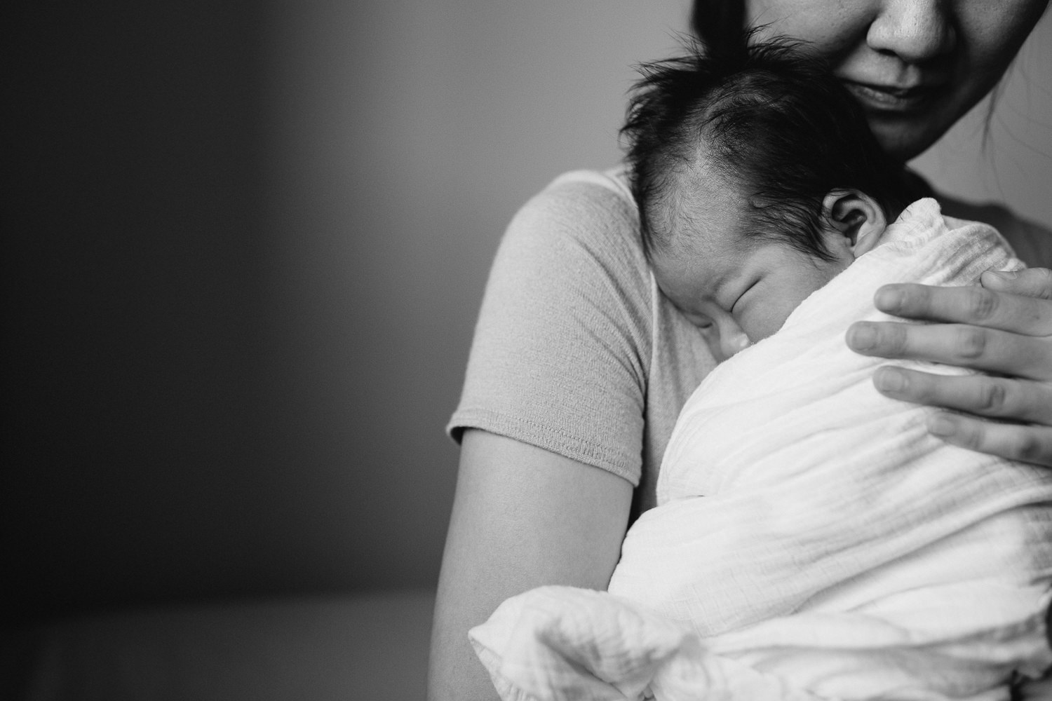 new mother cuddles 2 week old baby son in swaddle to chest - Uxbridge In-Home Photography