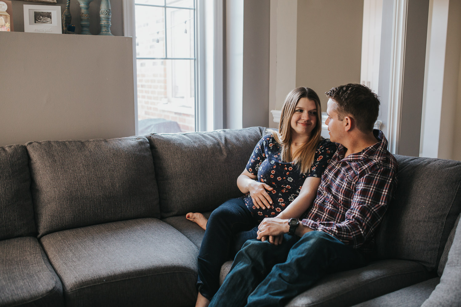 expecting couple snuggles on couch, pregnant mom holding baby belly - Stouffville Lifestyle Photography