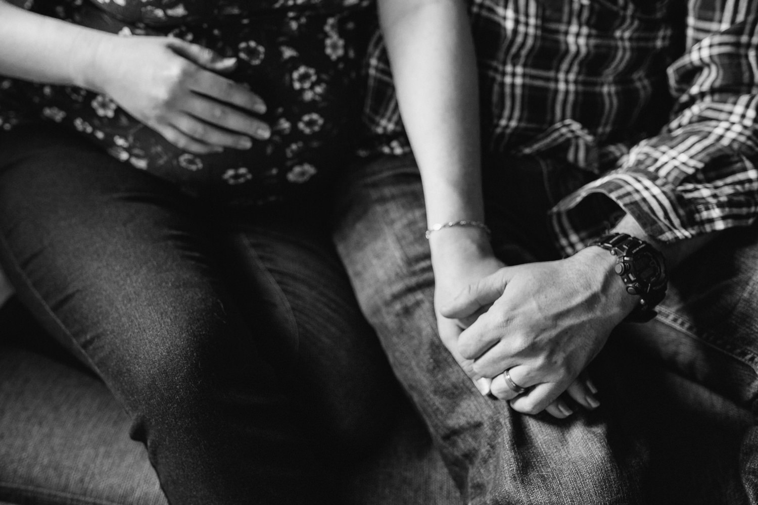 expecting couple snuggles on couch, pregnant mom holding baby belly, close up of hands - Markham Lifestyle Photography