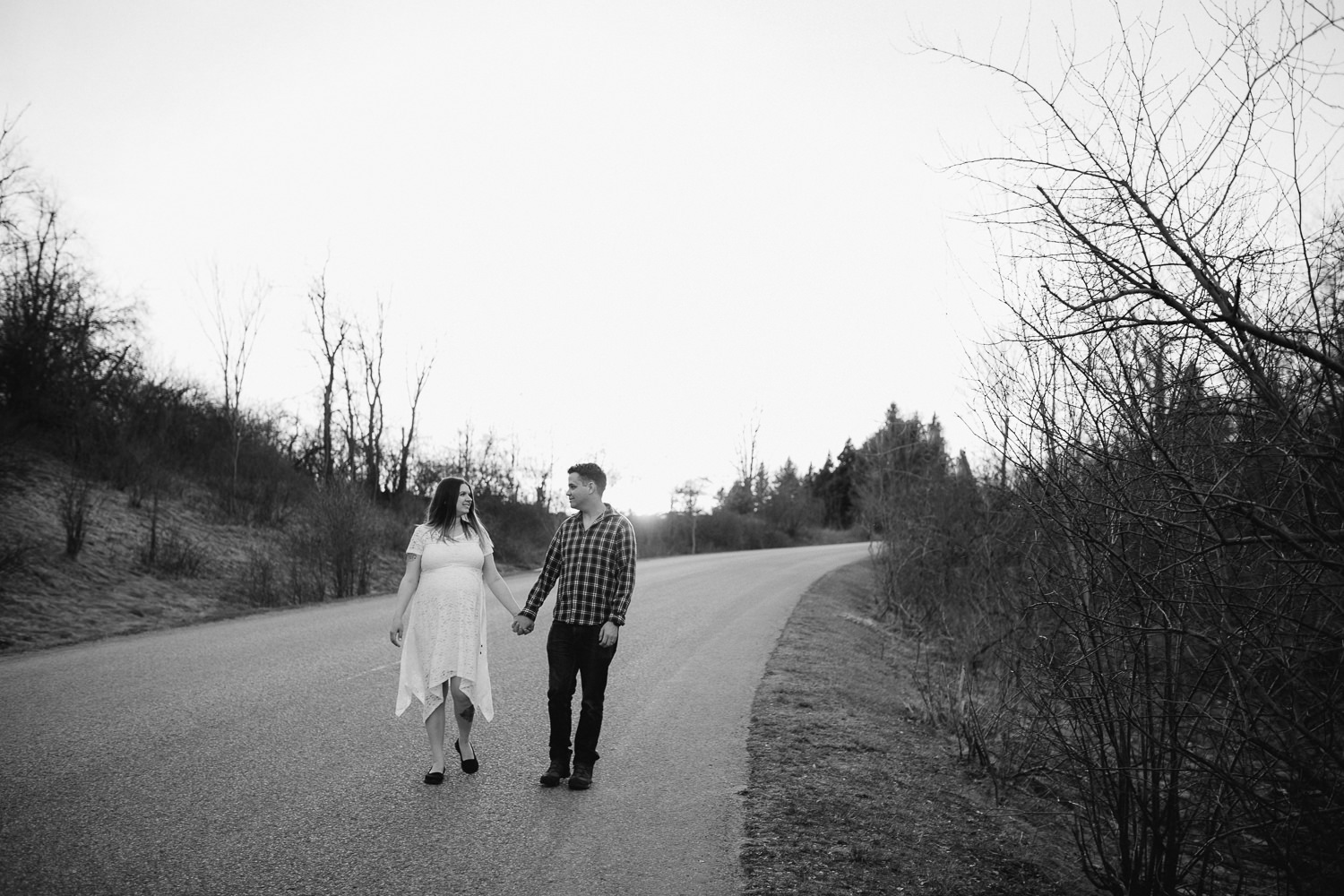 husband and pregnant wife walk down road holding hands - Newmarket Lifestyle Photos