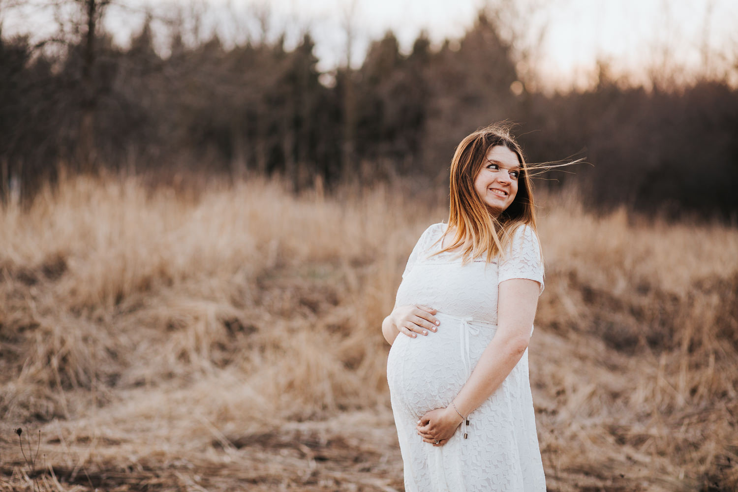 pregnant mom-to-be holds baby belly and looks behind her - Barrie Lifestyle Photography